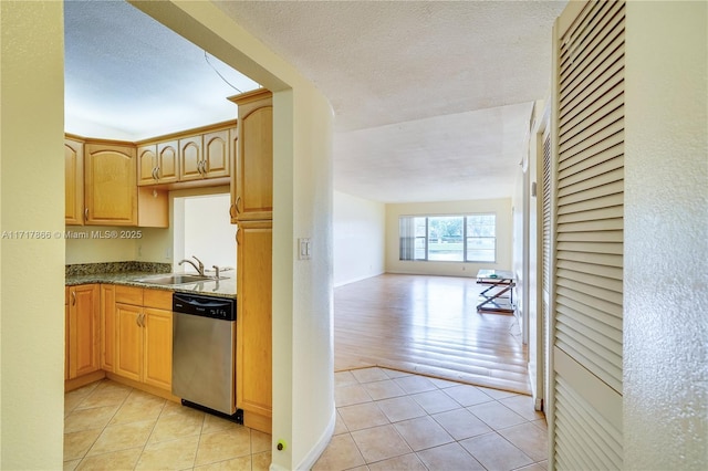 kitchen with sink, stainless steel dishwasher, a textured ceiling, light brown cabinetry, and light tile patterned flooring