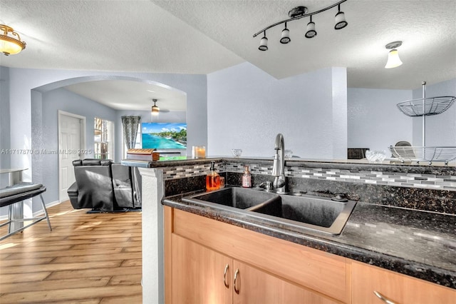 kitchen featuring ceiling fan, sink, a textured ceiling, light brown cabinetry, and light wood-type flooring