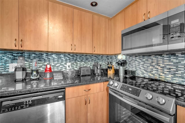 kitchen featuring decorative backsplash, appliances with stainless steel finishes, a textured ceiling, and dark stone counters