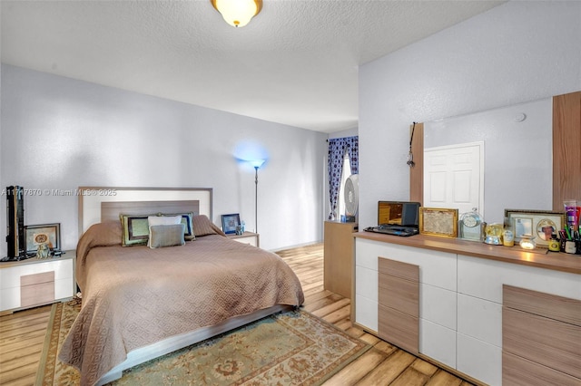 bedroom with light hardwood / wood-style floors and a textured ceiling