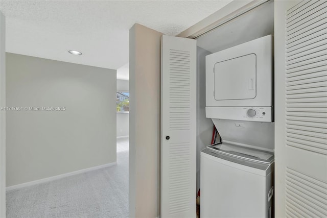 clothes washing area featuring a textured ceiling and stacked washer / drying machine