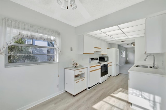 kitchen with a wealth of natural light, white cabinets, sink, and white appliances