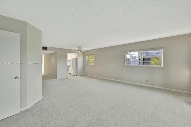 empty room featuring ceiling fan, light colored carpet, and a textured ceiling