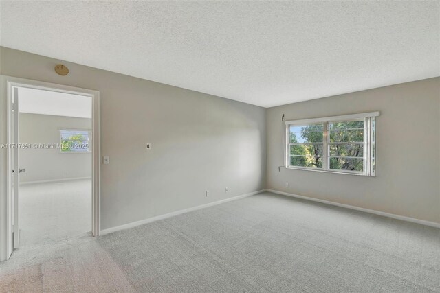 unfurnished room with light colored carpet and a textured ceiling