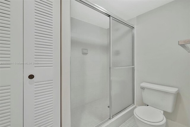 bathroom with toilet, tile patterned floors, and a shower with shower door