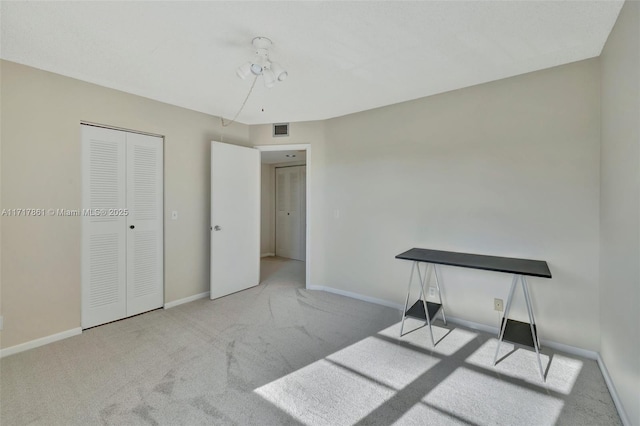 unfurnished bedroom featuring light colored carpet and a closet