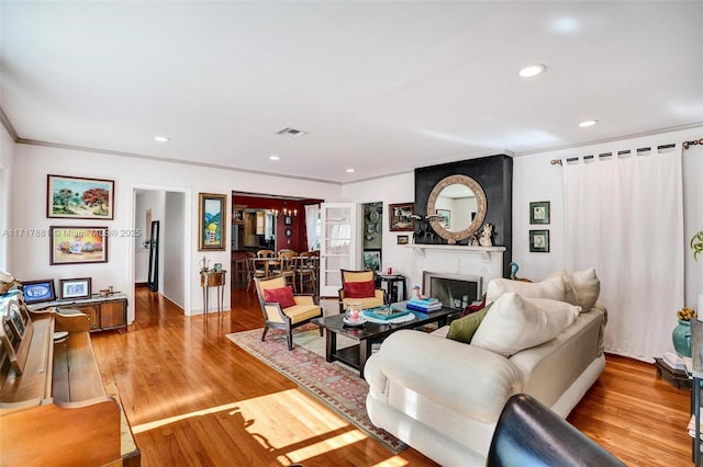 living room with a fireplace, ornamental molding, and light hardwood / wood-style floors