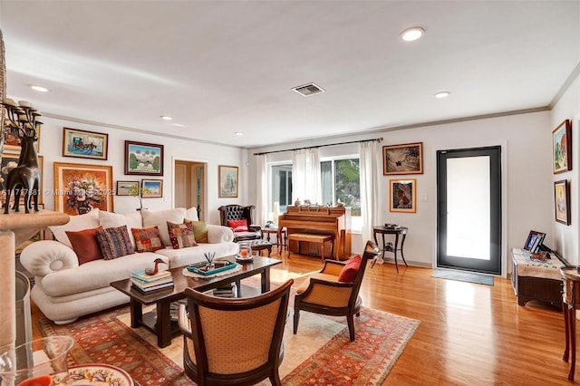 living room with light wood-type flooring and crown molding