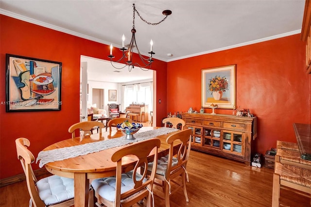 dining space featuring hardwood / wood-style floors, a chandelier, and crown molding