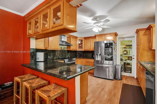 kitchen featuring a kitchen bar, crown molding, stainless steel appliances, wall chimney exhaust hood, and kitchen peninsula