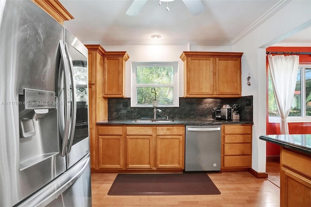 kitchen featuring appliances with stainless steel finishes, sink, light hardwood / wood-style floors, crown molding, and tasteful backsplash