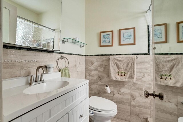 bathroom with vanity, tile walls, and toilet