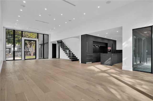 unfurnished living room with expansive windows, light wood-type flooring, and sink