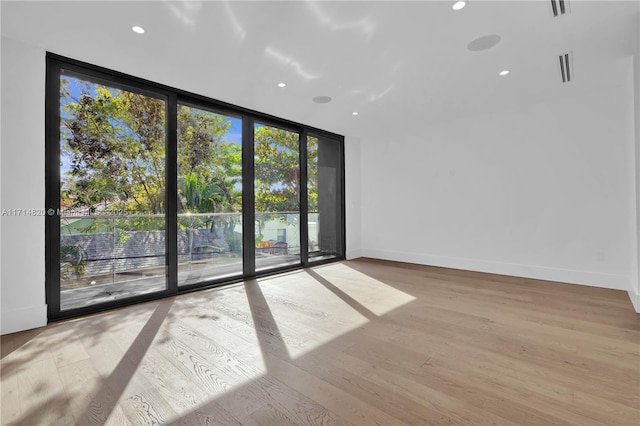 unfurnished room featuring expansive windows and light hardwood / wood-style floors