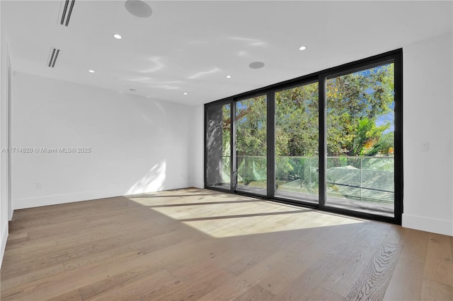 unfurnished room featuring light wood-type flooring and a wall of windows