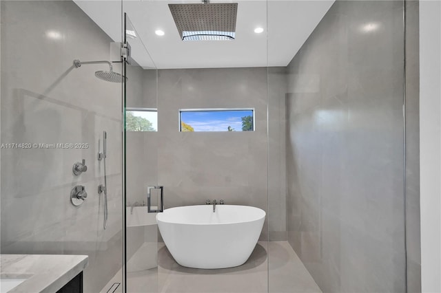 bathroom with shower with separate bathtub, vanity, and tile walls