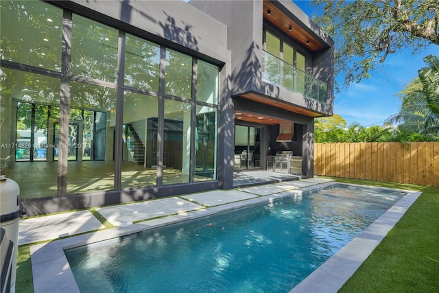 rear view of house with a patio area, a fenced in pool, and exterior kitchen