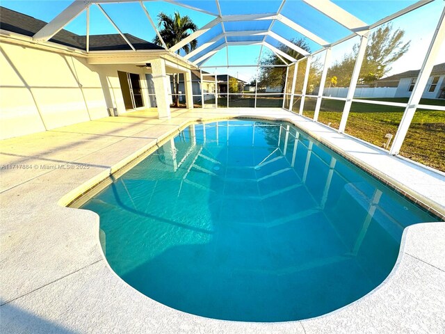 view of swimming pool featuring a lawn, glass enclosure, and a patio