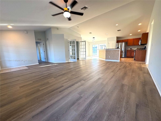 unfurnished living room featuring dark hardwood / wood-style floors, ceiling fan, and vaulted ceiling