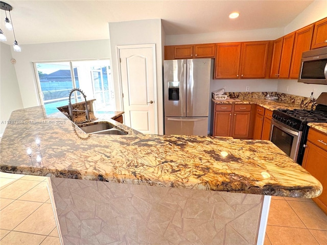 kitchen featuring light tile patterned floors, an island with sink, stainless steel appliances, and sink