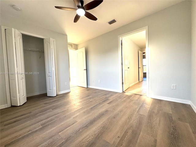 unfurnished bedroom featuring hardwood / wood-style floors, a closet, and ceiling fan