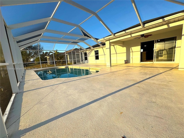 view of pool with a patio, glass enclosure, and ceiling fan