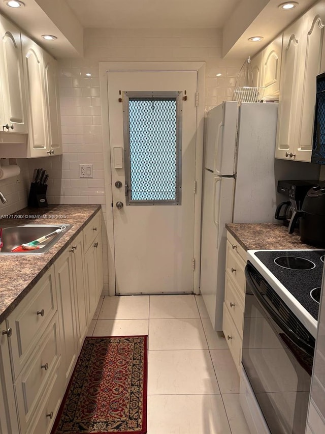 kitchen with white cabinets, light tile patterned flooring, sink, and black range with electric cooktop