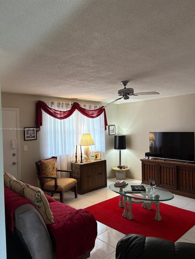 living room with ceiling fan, light tile patterned floors, and a textured ceiling