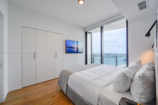 bedroom with access to exterior, light hardwood / wood-style floors, and floor to ceiling windows