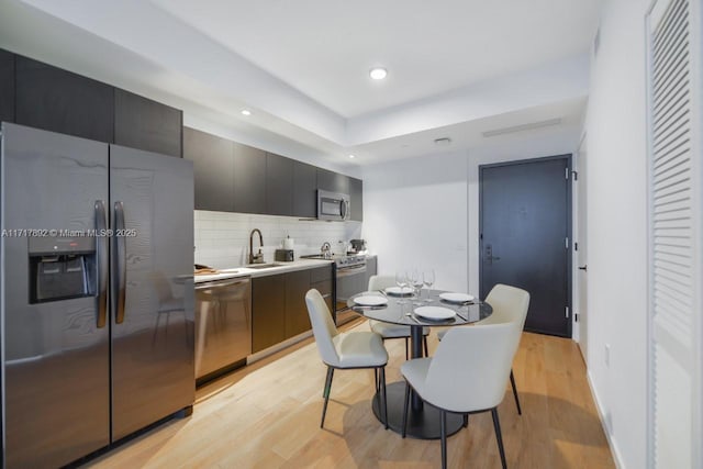 kitchen featuring tasteful backsplash, sink, light hardwood / wood-style floors, and appliances with stainless steel finishes