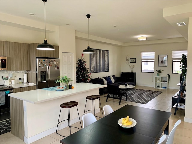 kitchen featuring a breakfast bar area, light tile patterned flooring, stainless steel appliances, and decorative light fixtures