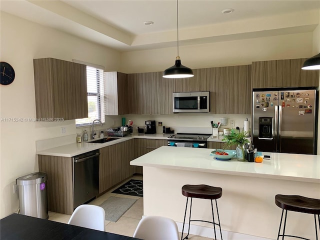 kitchen featuring appliances with stainless steel finishes, a breakfast bar, sink, pendant lighting, and light tile patterned flooring