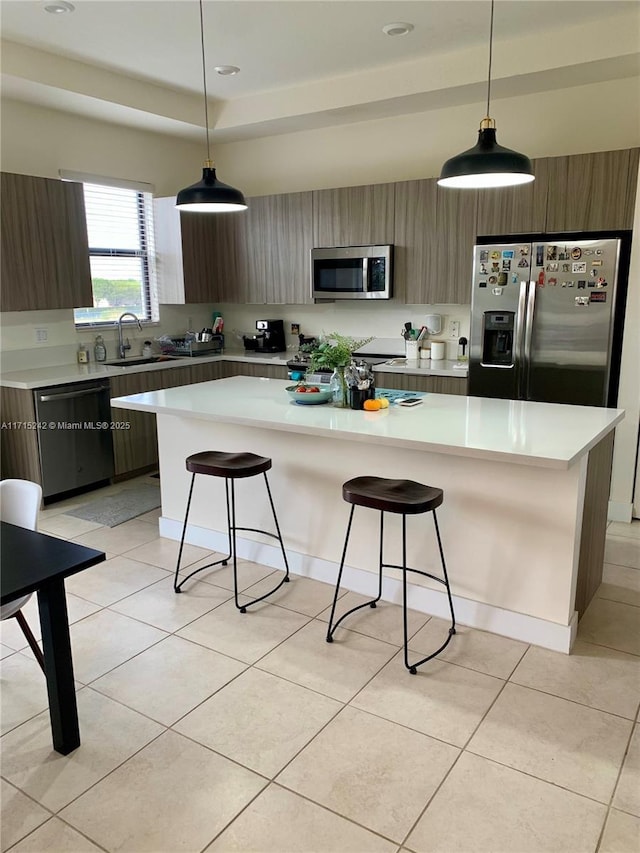 kitchen with hanging light fixtures, a kitchen island, stainless steel appliances, and sink