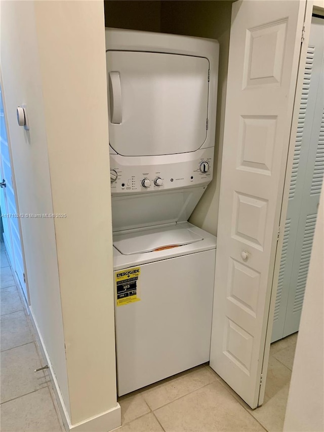 clothes washing area featuring light tile patterned floors and stacked washer / dryer