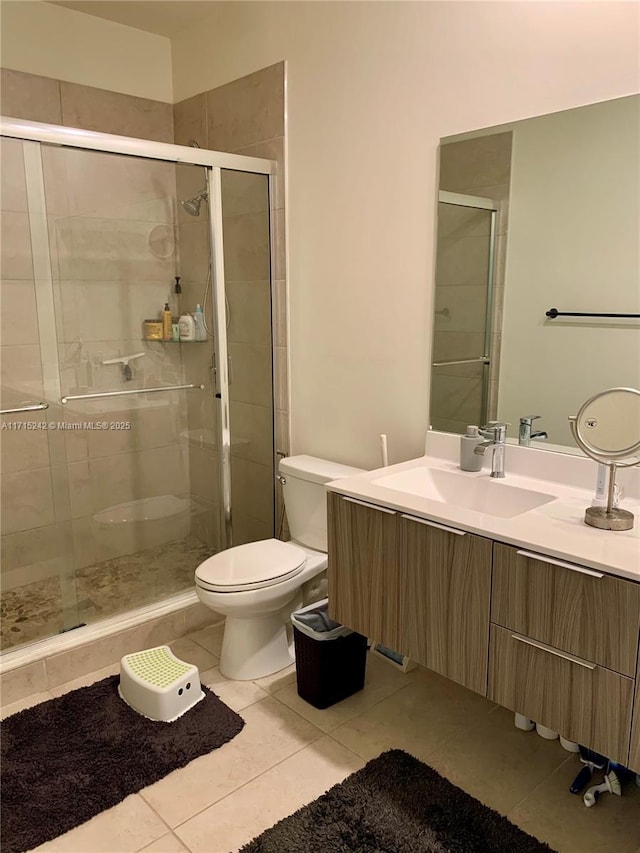 bathroom featuring tile patterned floors, vanity, a shower with shower door, and toilet