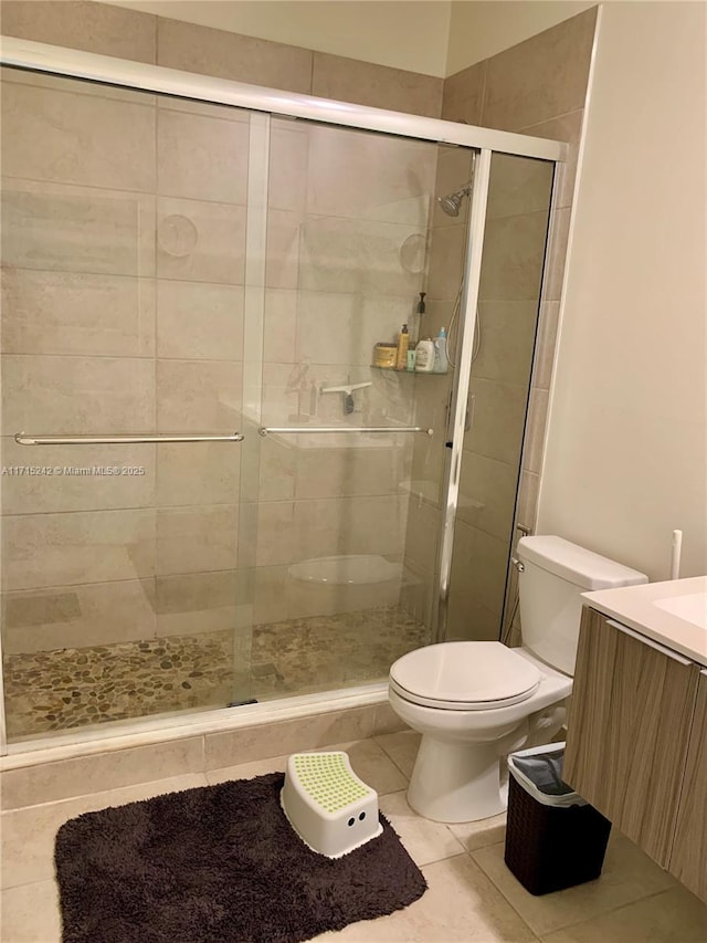 bathroom with tile patterned floors, vanity, toilet, and an enclosed shower