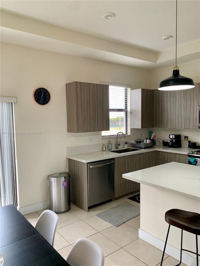 kitchen with sink, light tile patterned floors, appliances with stainless steel finishes, a tray ceiling, and decorative light fixtures