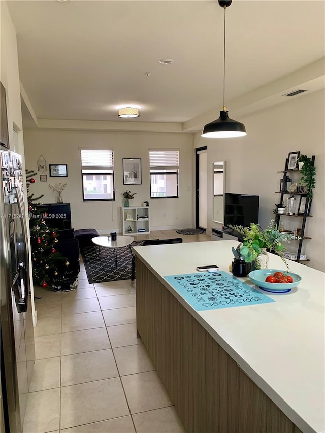 kitchen with stainless steel fridge with ice dispenser, light tile patterned floors, and hanging light fixtures