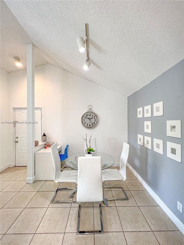 dining room featuring lofted ceiling, light tile patterned flooring, and a textured ceiling