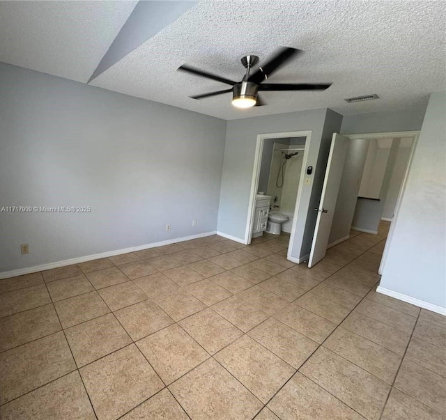 spare room featuring ceiling fan, light tile patterned floors, and a textured ceiling