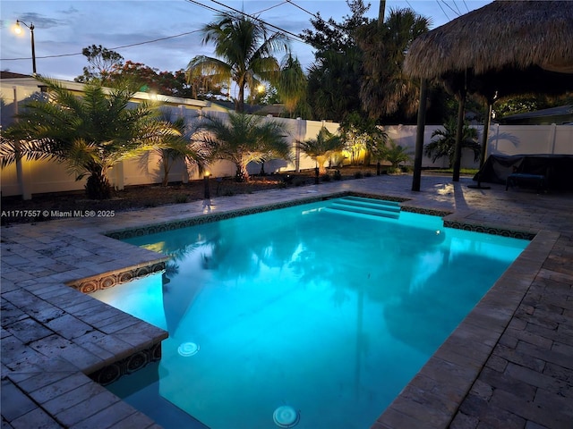 pool at dusk featuring a patio