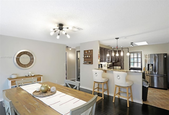 dining space featuring a textured ceiling, a skylight, an inviting chandelier, and dark wood-type flooring