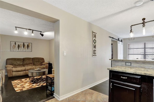 interior space with a barn door, light stone counters, light tile patterned floors, and a textured ceiling