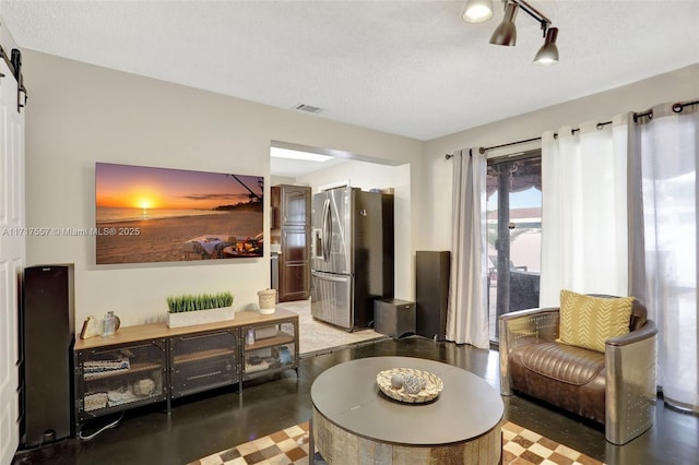 living room featuring a barn door and a textured ceiling