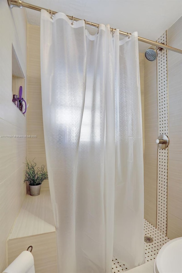 bathroom featuring curtained shower and tile walls