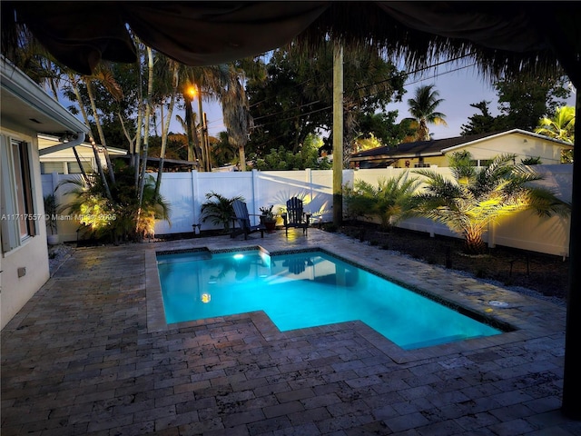 pool at dusk featuring a patio area