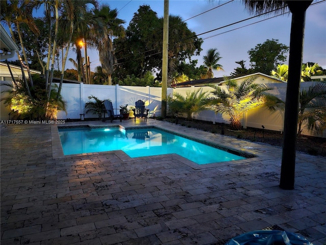 pool at dusk with a patio area