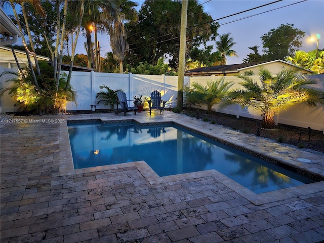 pool at dusk featuring a patio area