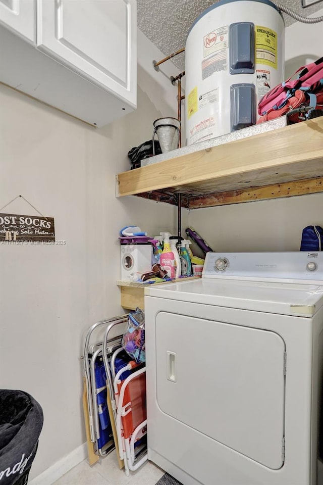 clothes washing area with washer / clothes dryer, electric water heater, light tile patterned flooring, and cabinets