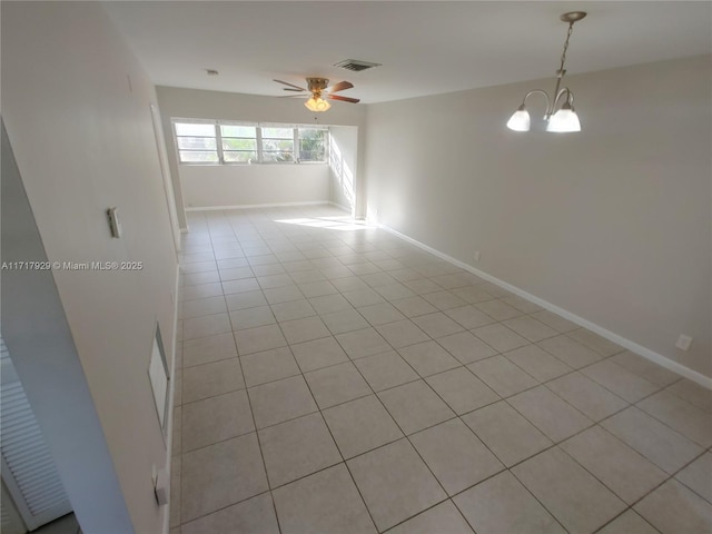 spare room featuring ceiling fan with notable chandelier and light tile patterned floors